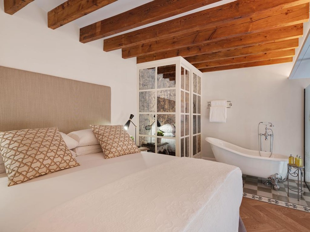 Example of a farmhouse master light wood floor and beige floor bedroom design in Paris with white walls