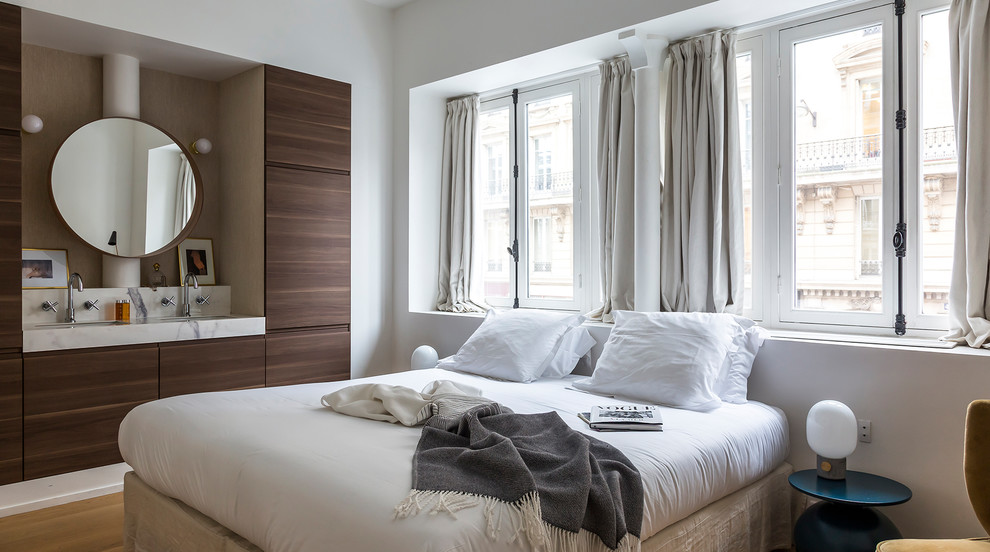Example of a trendy master light wood floor and beige floor bedroom design in Paris with white walls