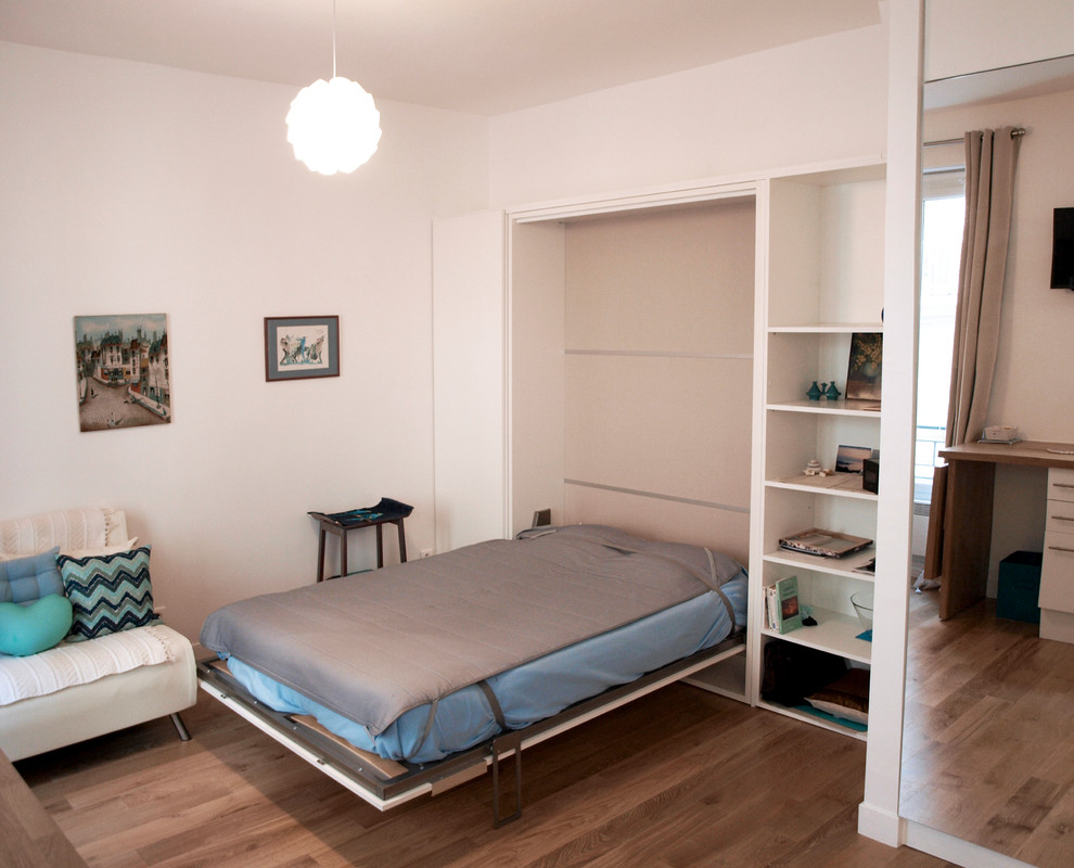 Small scandi master bedroom in Paris with white walls, light hardwood flooring, no fireplace and beige floors.