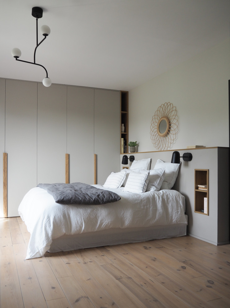 Cette photo montre une chambre parentale tendance de taille moyenne avec un mur blanc, un sol en bois brun et un sol beige.