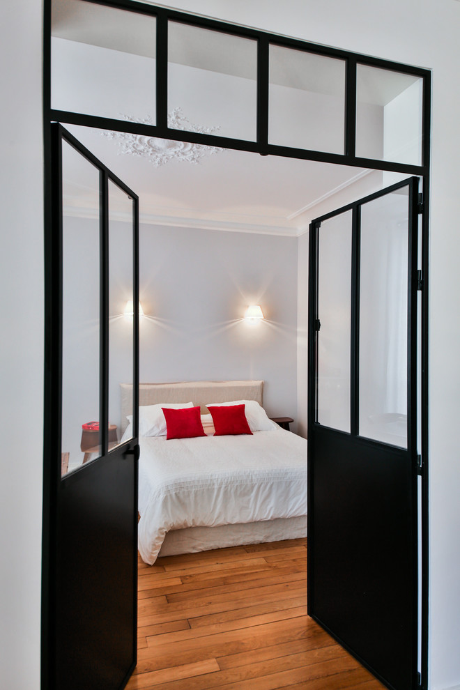Photo of a medium sized bohemian master bedroom in Paris with medium hardwood flooring and beige walls.