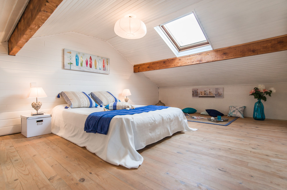 Imagen de dormitorio marinero con paredes blancas, suelo de madera clara y techo inclinado