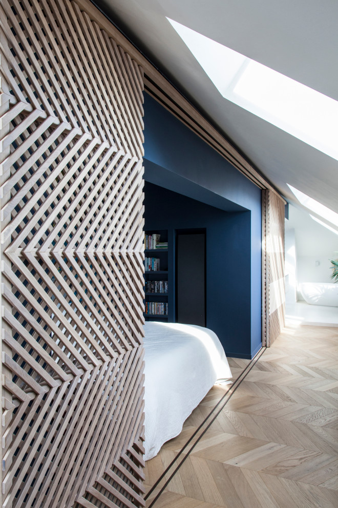パリにある巨大なコンテンポラリースタイルのおしゃれな主寝室 (青い壁、淡色無垢フローリング、暖炉なし、茶色い床)