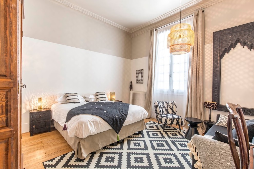 Imagen de dormitorio bohemio con paredes beige, suelo de madera en tonos medios y suelo marrón