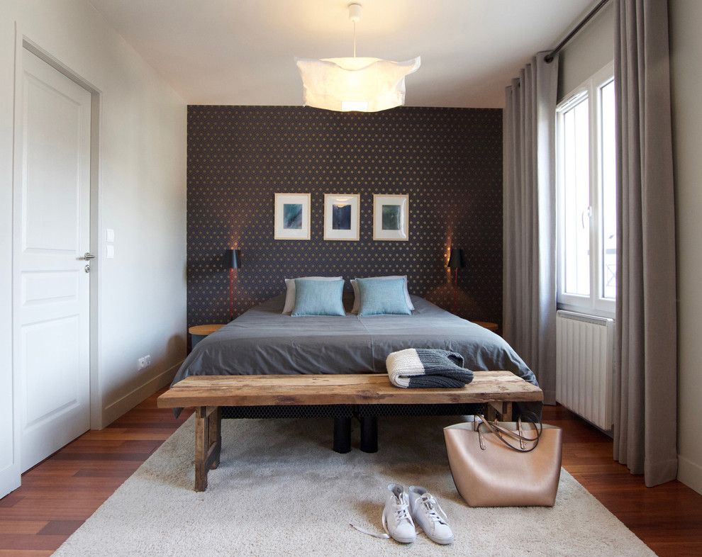 This is an example of a medium sized contemporary bedroom in Paris with white walls, medium hardwood flooring and no fireplace.