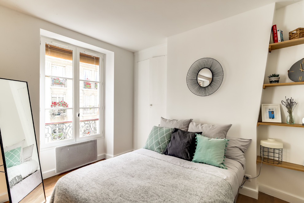 Immagine di una piccola camera matrimoniale minimalista con pareti bianche, parquet chiaro, nessun camino e pavimento marrone