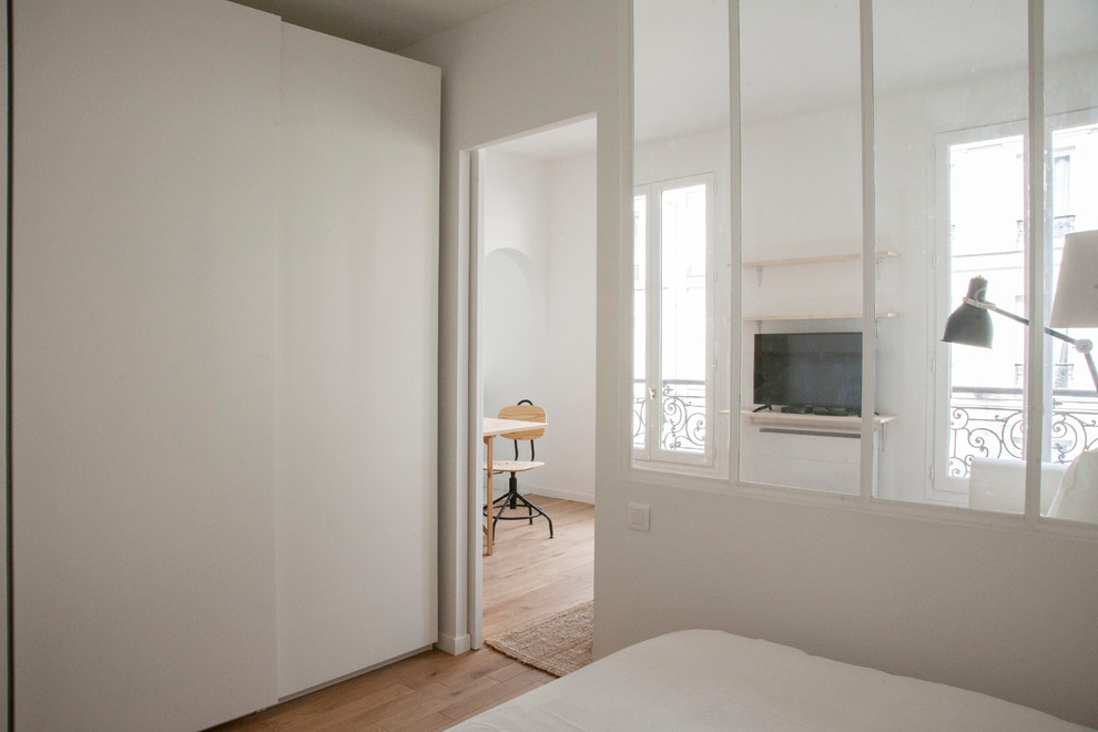 Design ideas for a medium sized contemporary master bedroom in Paris with white walls, medium hardwood flooring and brown floors.