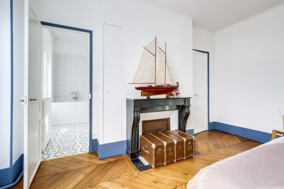 Inspiration for a mid-sized 1950s master light wood floor and brown floor bedroom remodel in Paris with white walls, no fireplace and a stone fireplace