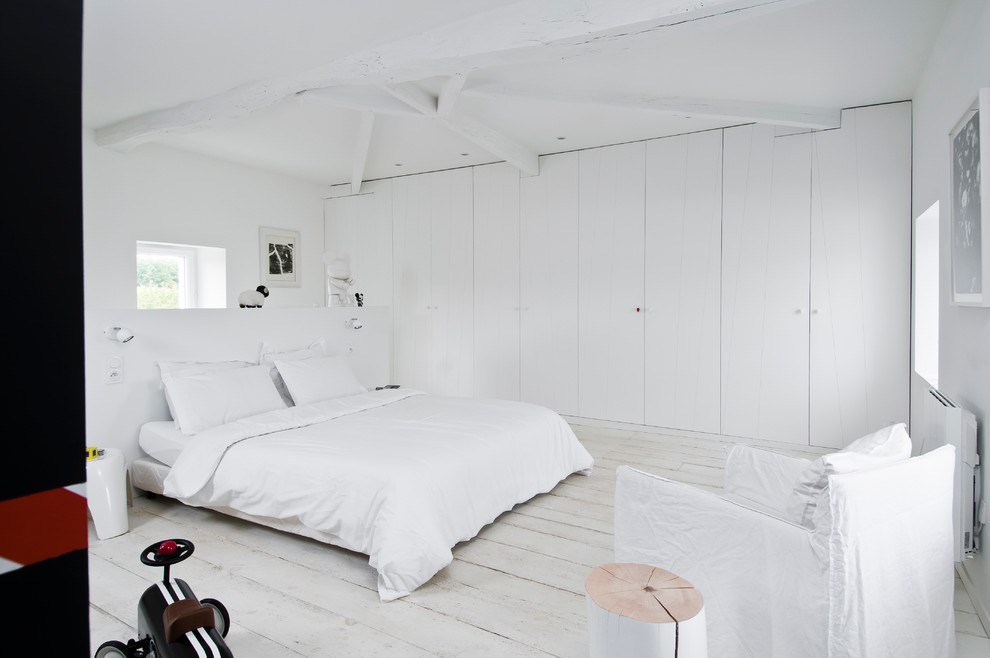 Scandi bedroom in Paris with white walls and painted wood flooring.