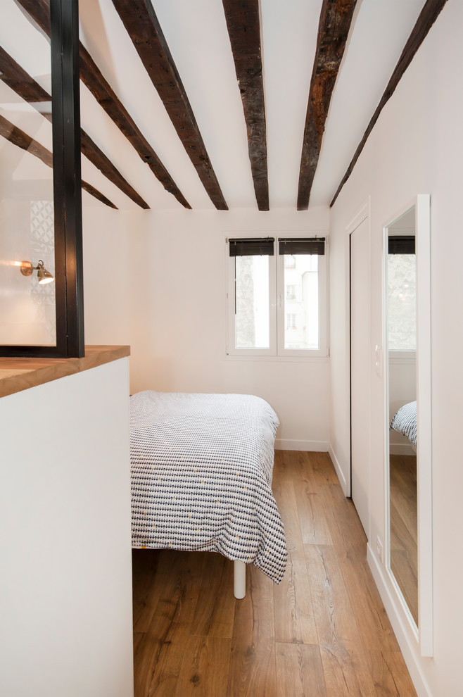 Réalisation d'une chambre parentale design de taille moyenne avec un mur blanc, un sol en bois brun et un sol beige.