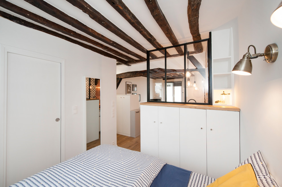 Modelo de dormitorio principal contemporáneo de tamaño medio con paredes blancas, suelo de madera en tonos medios y suelo beige