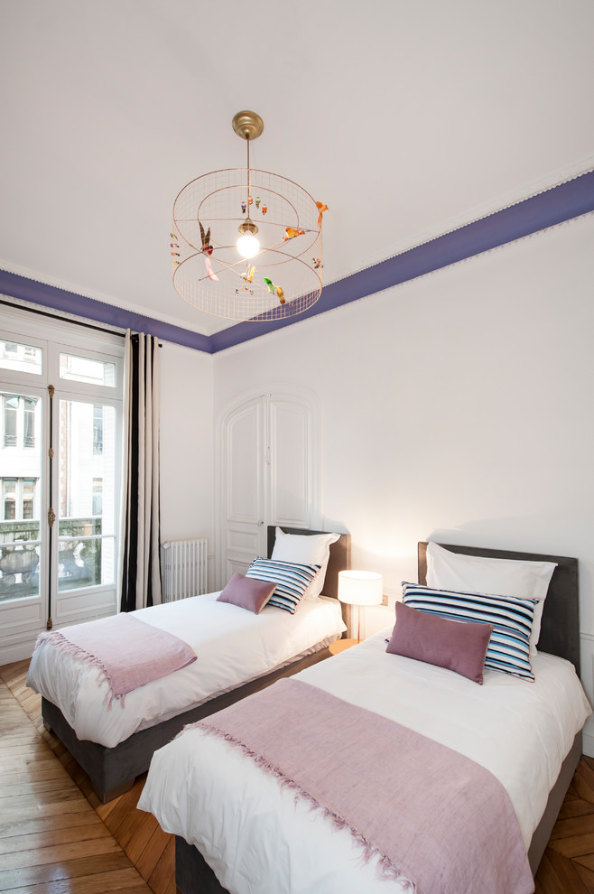 Cette image montre une chambre d'amis design de taille moyenne avec un mur blanc, un sol en bois brun et une cheminée standard.