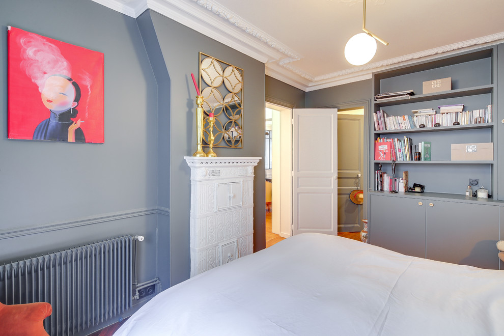 Ejemplo de dormitorio principal ecléctico de tamaño medio con paredes grises, suelo de madera clara, estufa de leña, marco de chimenea de baldosas y/o azulejos y suelo marrón