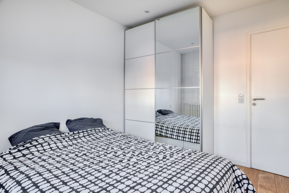 Cette photo montre une chambre tendance de taille moyenne avec un mur blanc, parquet clair et un sol marron.