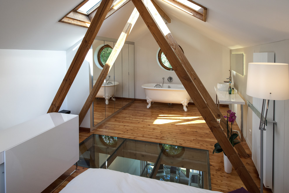 Inspiration pour une chambre parentale design de taille moyenne avec un mur blanc, un sol en bois brun et un sol marron.