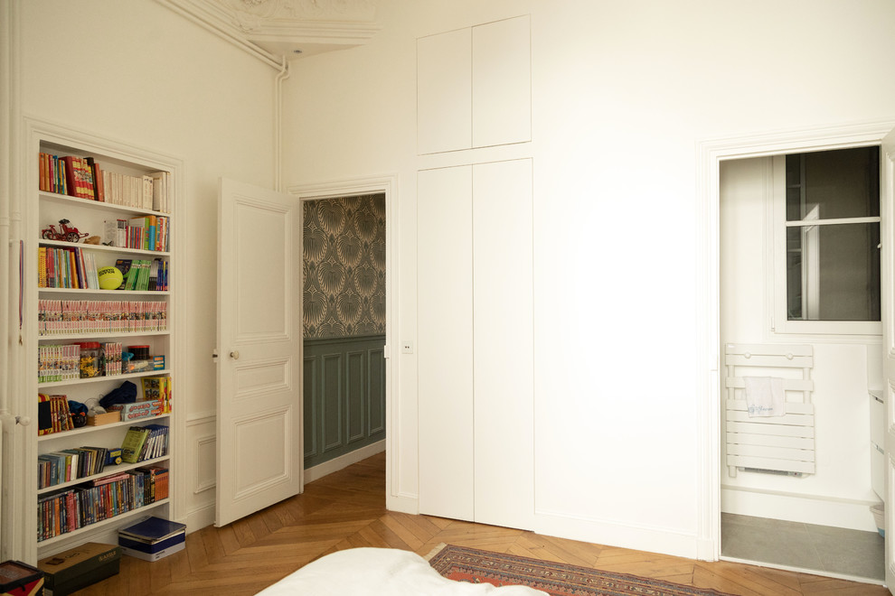 Cette image montre une chambre parentale design de taille moyenne avec un mur blanc, un sol en bois brun, un sol marron et aucune cheminée.