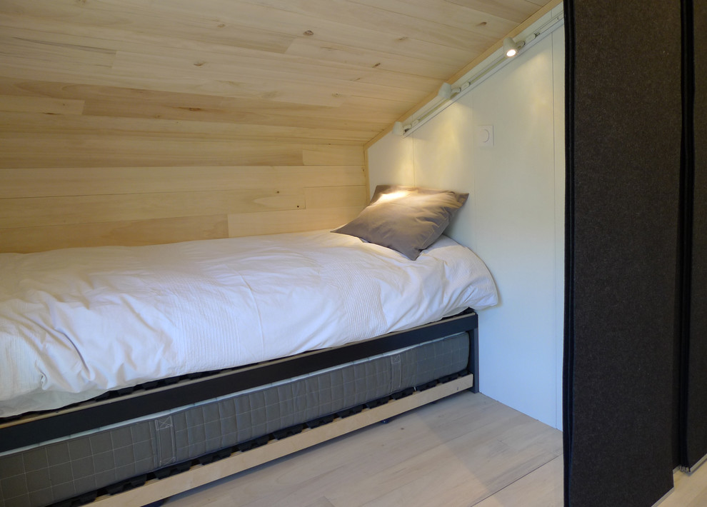 Diseño de dormitorio tipo loft actual pequeño sin chimenea con paredes negras y suelo de madera clara
