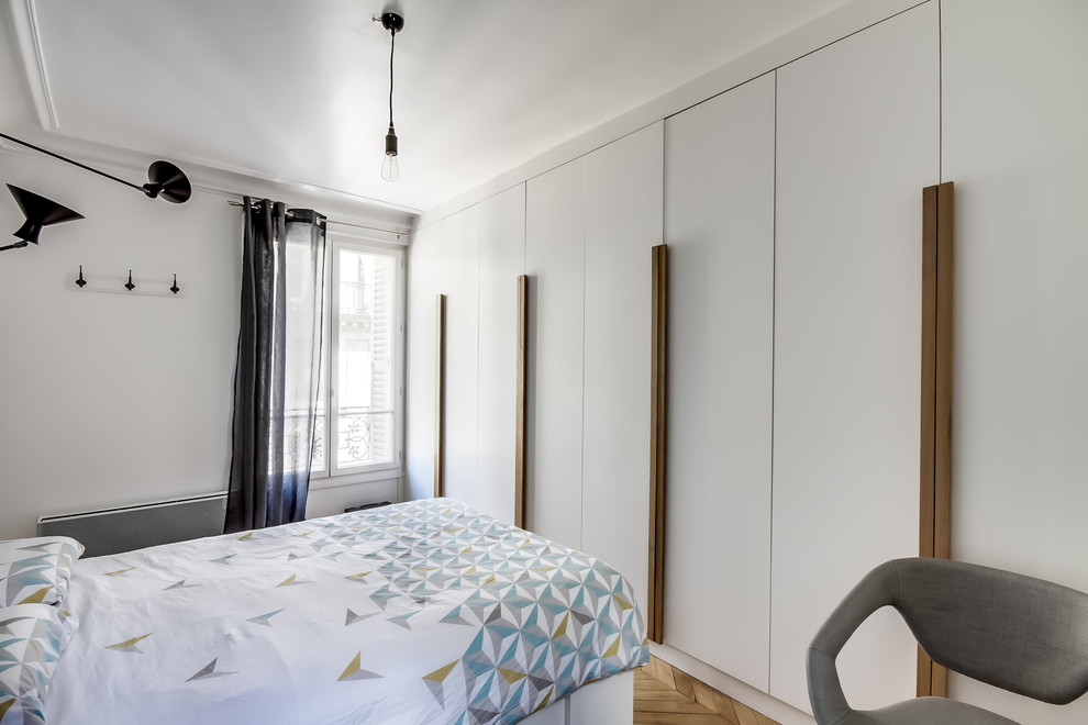 パリにある中くらいな北欧スタイルのおしゃれな主寝室 (白い壁、無垢フローリング、暖炉なし、茶色い床) のインテリア