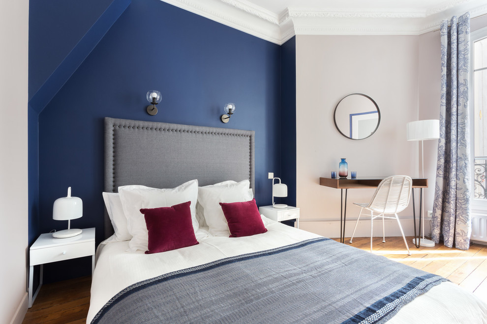 Modelo de dormitorio principal actual con paredes azules y suelo de madera en tonos medios