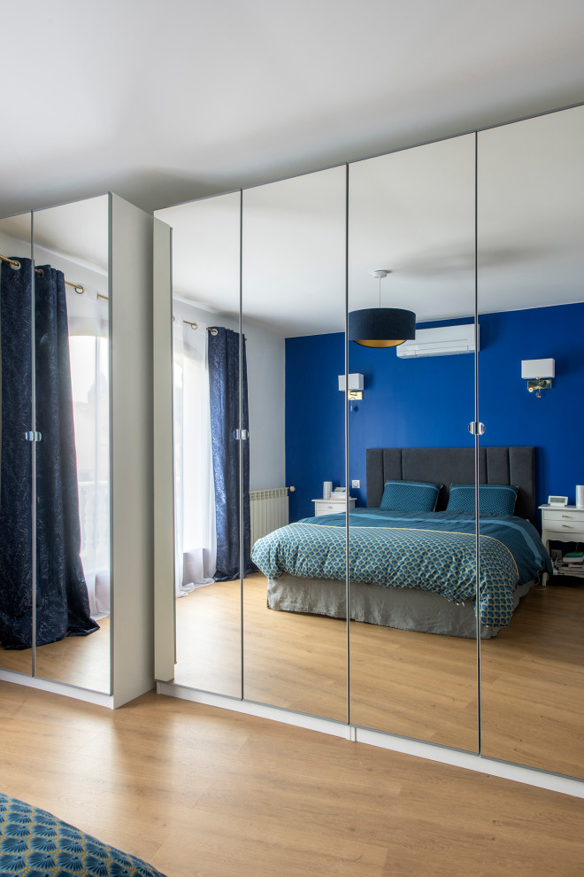Inspiration pour une chambre parentale minimaliste de taille moyenne avec un mur bleu, sol en stratifié, aucune cheminée et un sol beige.