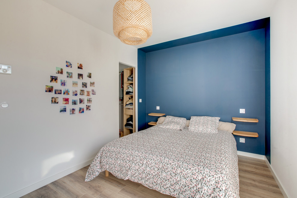 Ejemplo de dormitorio principal contemporáneo de tamaño medio con paredes azules, suelo laminado y suelo marrón