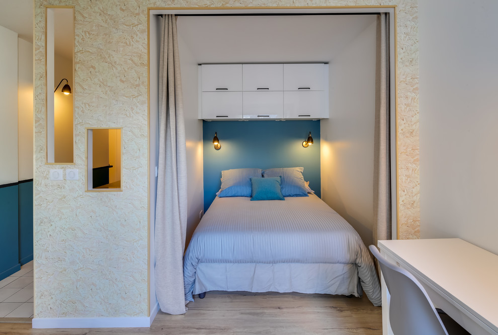 Idée de décoration pour une petite chambre parentale nordique avec un mur bleu et sol en stratifié.