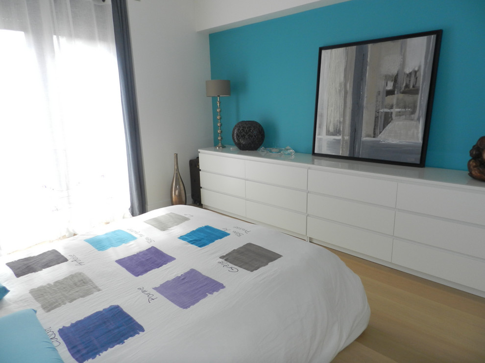 Imagen de dormitorio principal actual grande con paredes azules, suelo de madera clara y suelo beige