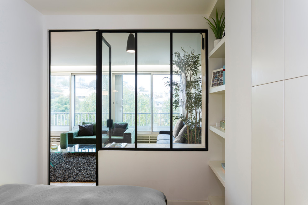 Example of a small danish master light wood floor bedroom design in Paris with white walls