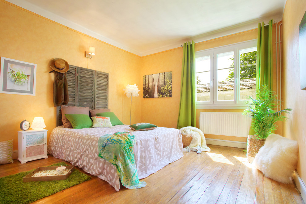 Idée de décoration pour une chambre parentale champêtre de taille moyenne avec un mur jaune et parquet clair.