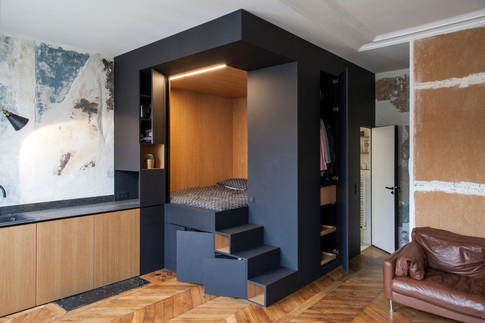 Diseño de dormitorio principal actual pequeño sin chimenea con paredes negras y suelo de madera oscura