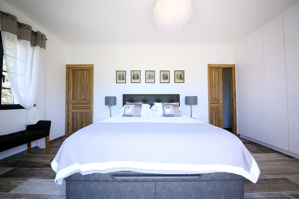 Ejemplo de dormitorio principal mediterráneo con paredes blancas y suelo marrón