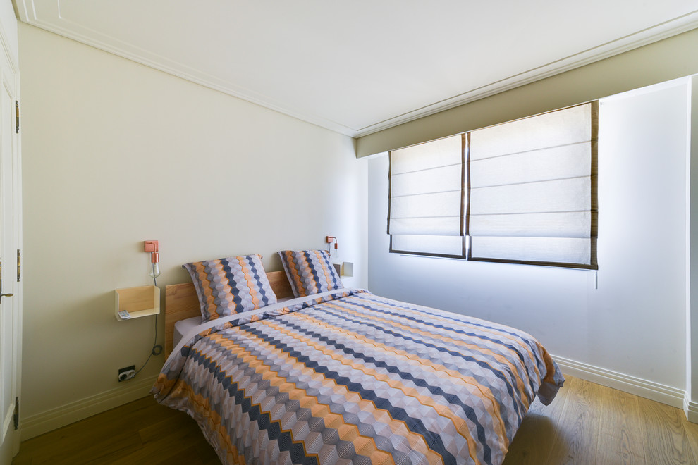 Ejemplo de dormitorio principal actual de tamaño medio sin chimenea con paredes beige, suelo de madera clara y suelo beige