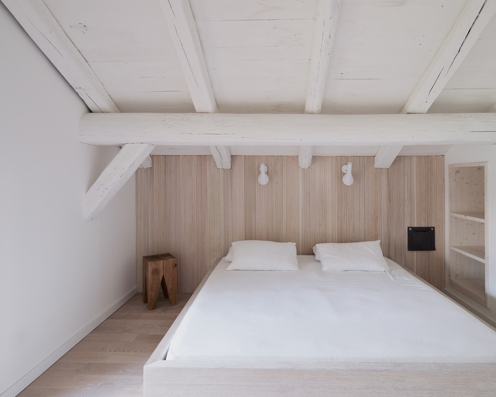 Modelo de dormitorio principal rústico de tamaño medio con paredes blancas y suelo de madera clara