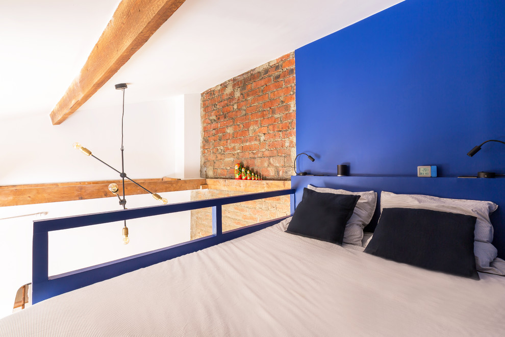 Ejemplo de dormitorio tipo loft industrial pequeño con paredes azules, suelo de madera en tonos medios y suelo marrón