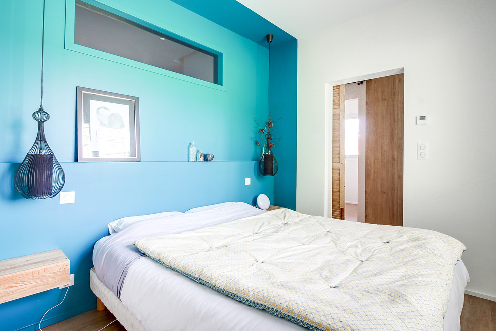Cette photo montre une chambre parentale moderne de taille moyenne avec un mur bleu, parquet clair, un sol beige et aucune cheminée.