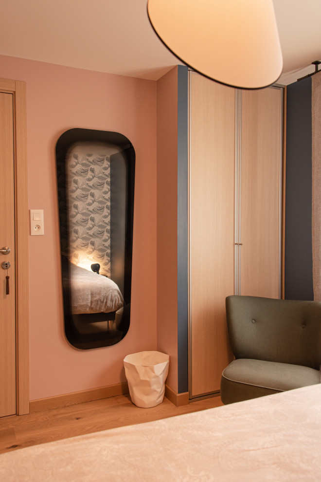 Immagine di una camera da letto minimalista con pareti rosa, parquet scuro e carta da parati