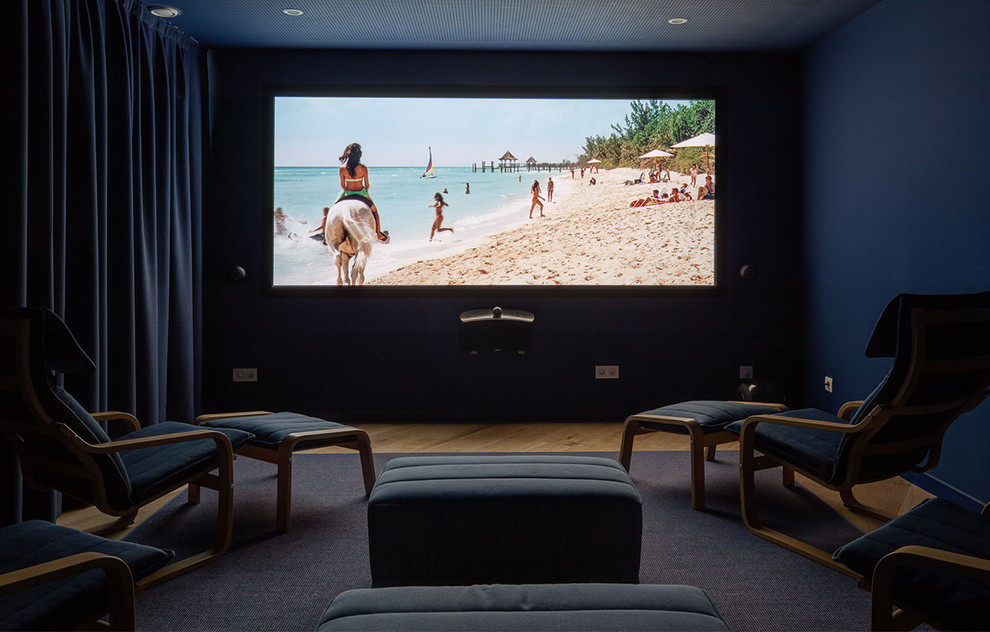 На фото: изолированный домашний кинотеатр среднего размера в стиле неоклассика (современная классика) с синими стенами, паркетным полом среднего тона и телевизором на стене с