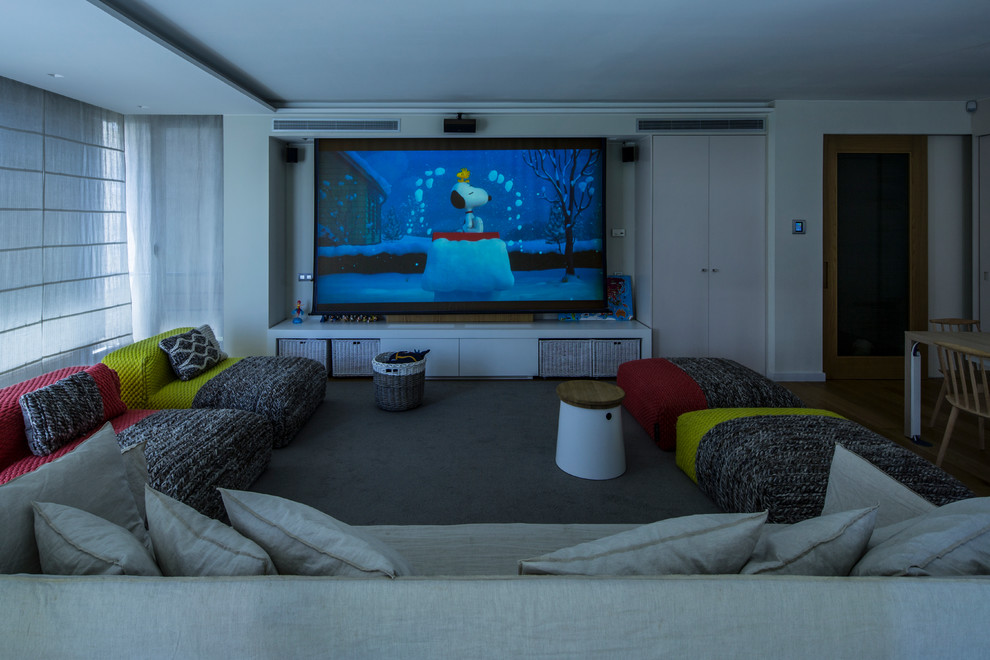 Ejemplo de cine en casa cerrado grande con paredes blancas, suelo de madera clara y televisor colgado en la pared