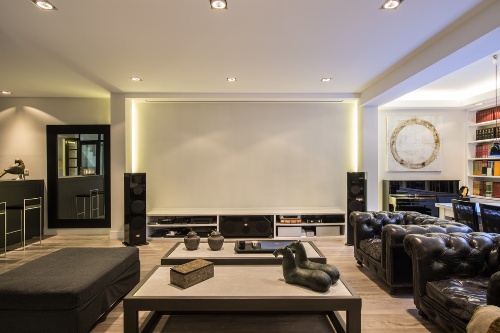 Inspiration for a large contemporary open plan home cinema in Madrid with white walls, medium hardwood flooring and a projector screen.