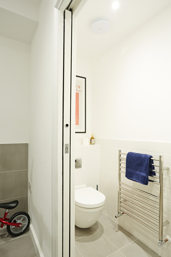 This is an example of a small contemporary cloakroom in London with a one-piece toilet, white walls and grey floors.