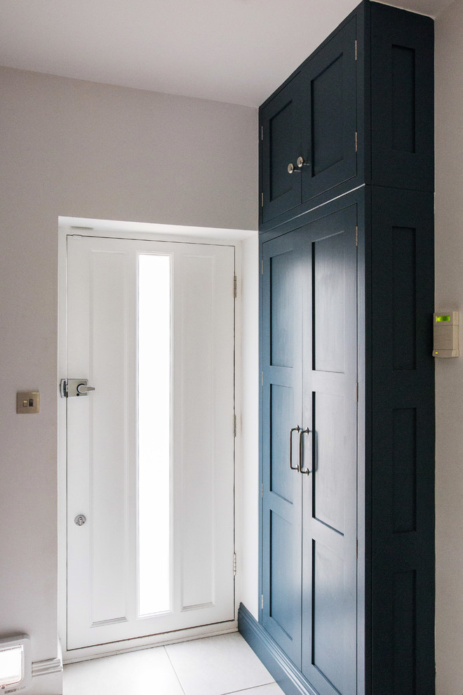 Modelo de aseo contemporáneo pequeño con armarios con paneles empotrados, puertas de armario azules, paredes blancas, suelo de piedra caliza, encimera de cuarcita y suelo beige