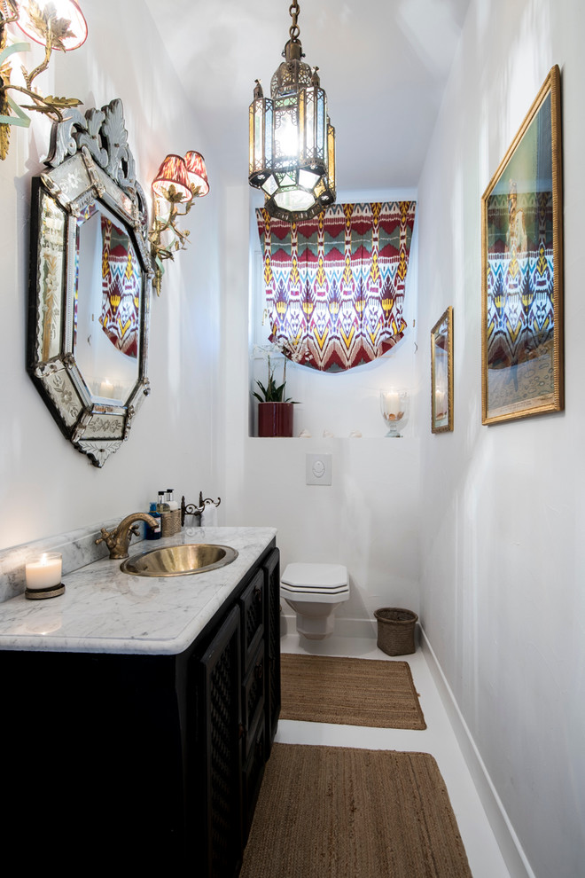 Mediterrane Gästetoilette mit verzierten Schränken, schwarzen Schränken, Wandtoilette, weißer Wandfarbe und Einbauwaschbecken in London