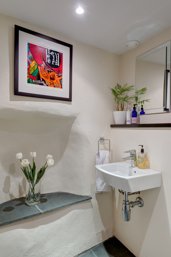 Inredning av ett medelhavsstil litet toalett, med ett väggmonterat handfat, vita väggar och skiffergolv