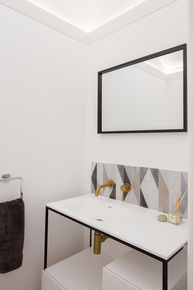 Modern inredning av ett litet toalett, med möbel-liknande, en toalettstol med hel cisternkåpa, flerfärgad kakel, beige väggar, klinkergolv i porslin och ett konsol handfat