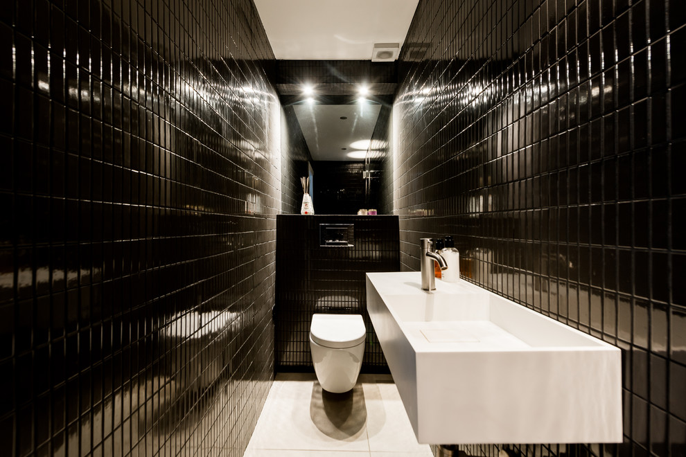 Свежая идея для дизайна: маленький туалет в современном стиле с унитазом-моноблоком, черной плиткой, керамической плиткой, черными стенами, полом из цементной плитки и подвесной раковиной для на участке и в саду - отличное фото интерьера