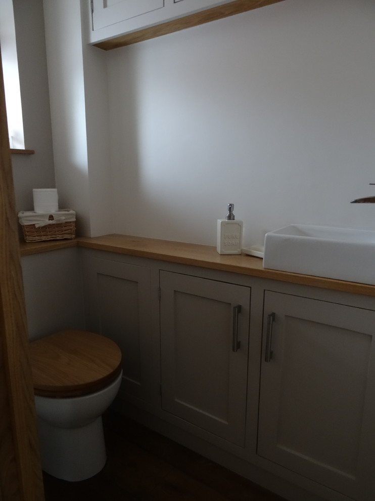 Kleine Klassische Gästetoilette mit Schrankfronten im Shaker-Stil, Wandtoilette, dunklem Holzboden und Waschtisch aus Holz in Hampshire