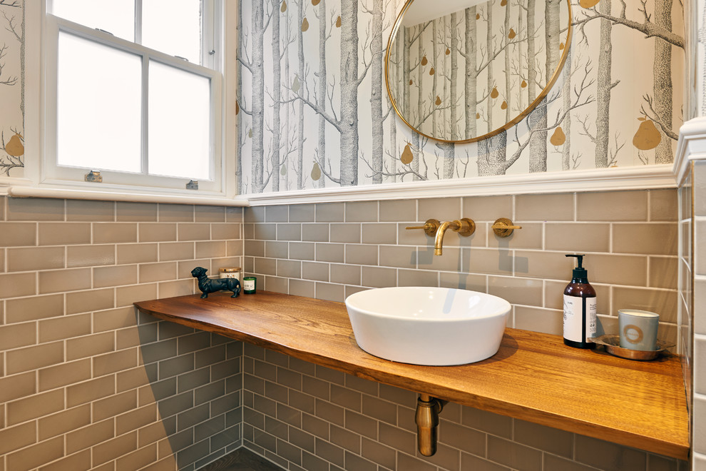 This is an example of a large bohemian cloakroom in London with open cabinets, medium wood cabinets, a one-piece toilet, grey tiles, metro tiles, grey walls, medium hardwood flooring, a console sink and wooden worktops.