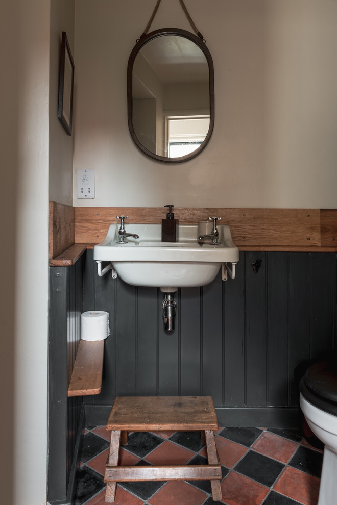 Cette image montre un WC et toilettes rustique avec un mur beige, un sol en carrelage de céramique et un lavabo suspendu.