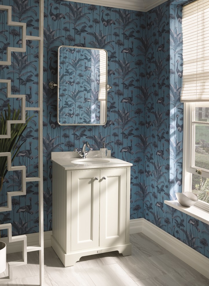 Eklektisk inredning av ett litet vit vitt toalett, med skåp i shakerstil, vita skåp, blå väggar, ett nedsänkt handfat, marmorbänkskiva och brunt golv