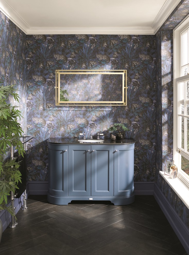 Cette image montre un WC et toilettes bohème de taille moyenne avec un placard à porte shaker, des portes de placard bleues, un mur multicolore, un lavabo posé, un plan de toilette en marbre, un sol marron et un plan de toilette noir.
